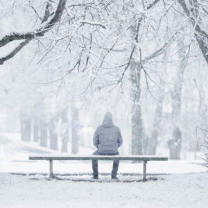 BRCA-Mutation Männer: Mann sitzt im Schnee auf einer Parkbank