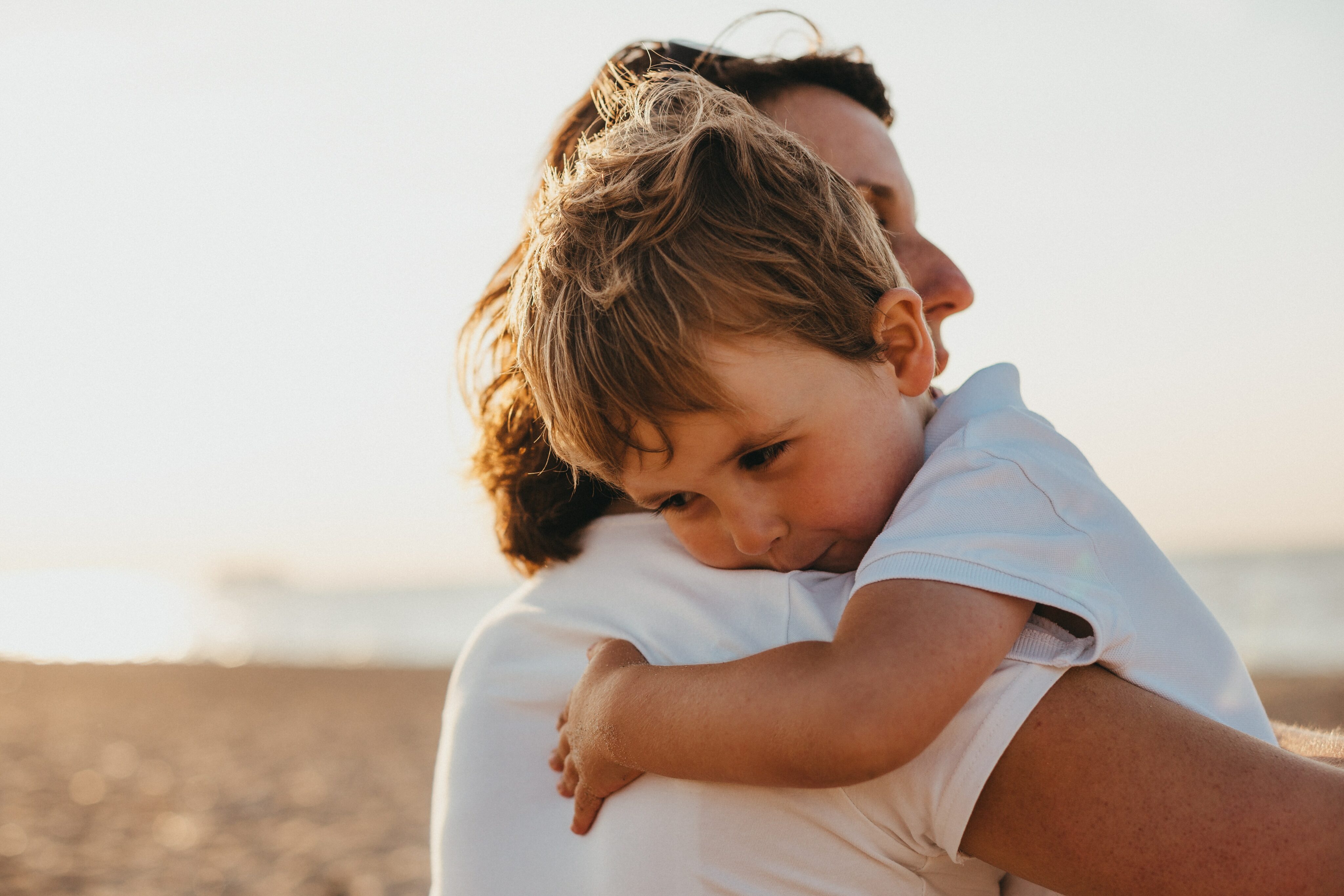 Cystische Fibrose Symptome:Junge umarmt seine Mutter am Strand