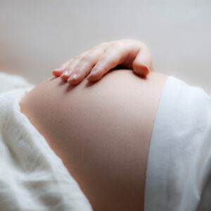 Schwangerschaftsdiabetes Symptome: Nahaufnahme einer Hand, die sanft über eine schwangere Bauchmitte streicht, symbolisch für Gesundheit und Fürsorge während der Schwangerschaft, einem kritischen Zeitraum für mütterliche und kindliche Gesundheit.