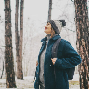 Gesundheit erhalten: Frau steht im winterlichen Wald