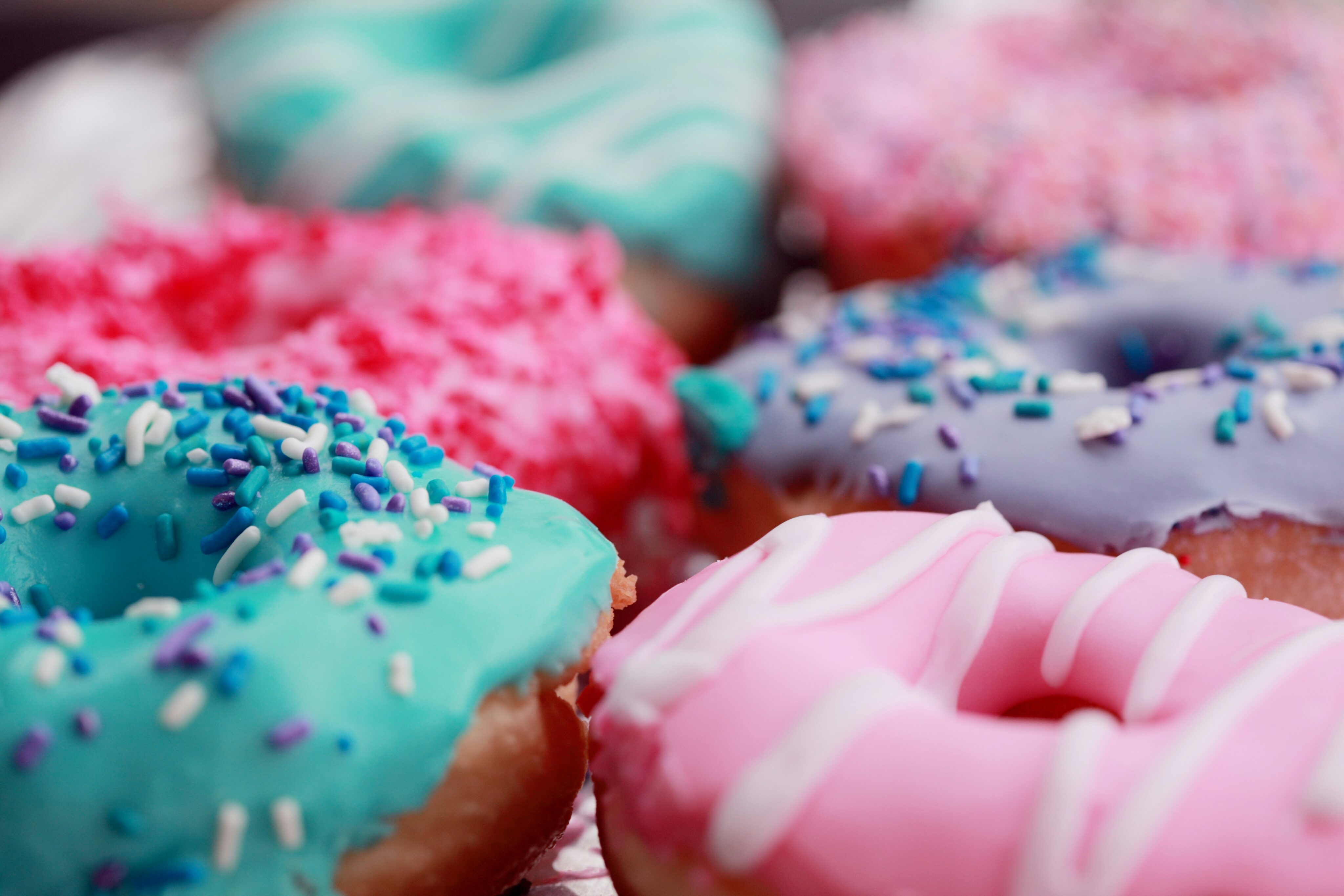 Diabetes mellitus Typ 2: Nahaufnahme von farbenfrohen Donuts mit Zuckerguss und Streuseln, ein verlockendes Bild, das jedoch die potenzielle Gefahr von zucker- und fettreichen Snacks für Menschen mit Diabetes mellitus Typ 2 symbolisiert