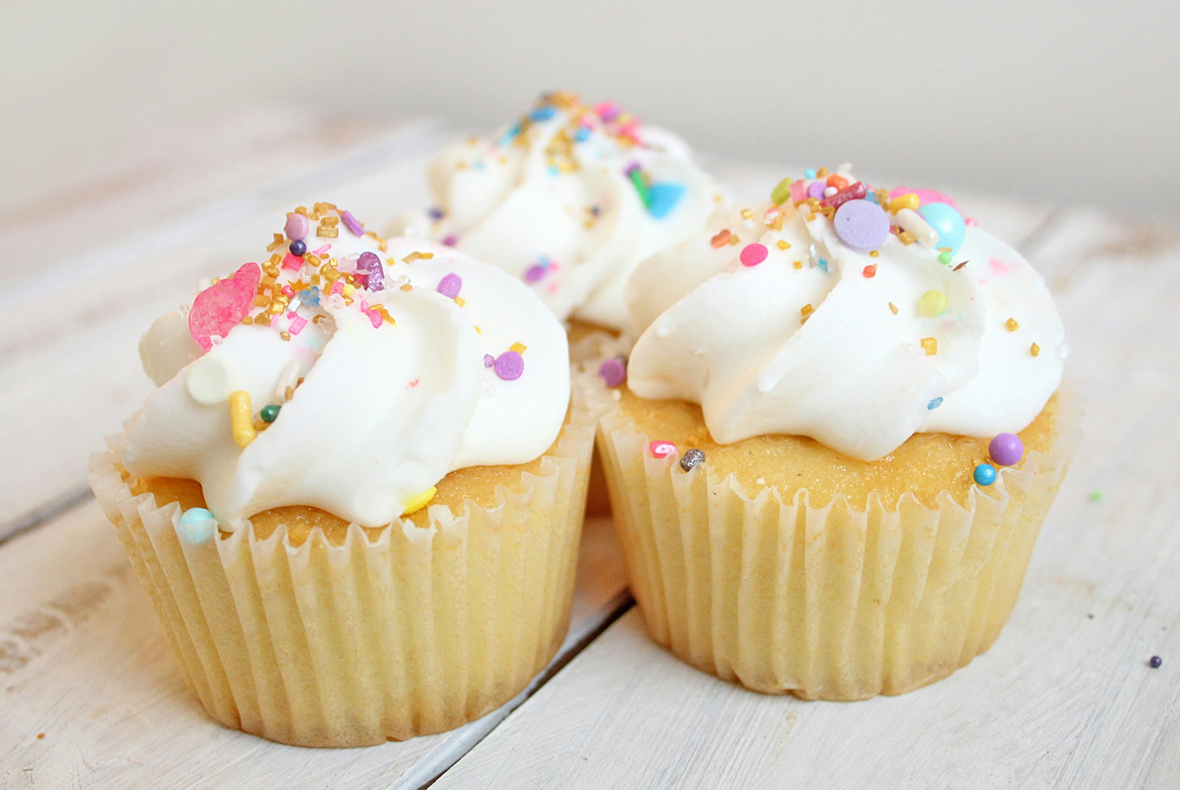 Metabolisches Syndrom Folgeerkrankungen: Zuckerreiche Cupcakes mit weißem Zuckerguss und bunten Streuseln, die als Beispiel für süße Lebensmittel dienen können, deren Konsum bei der Prävention von metabolischem Syndrom und dessen Folgeerkrankungen moderiert werden sollte.