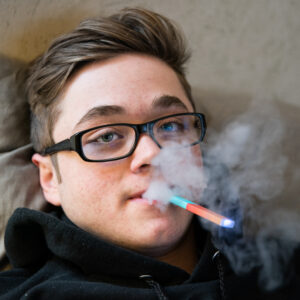 Jugendliche vapen: Junge raucht E-Zigarette