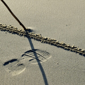 Fussabdruck mit gezogener Linie im Sand