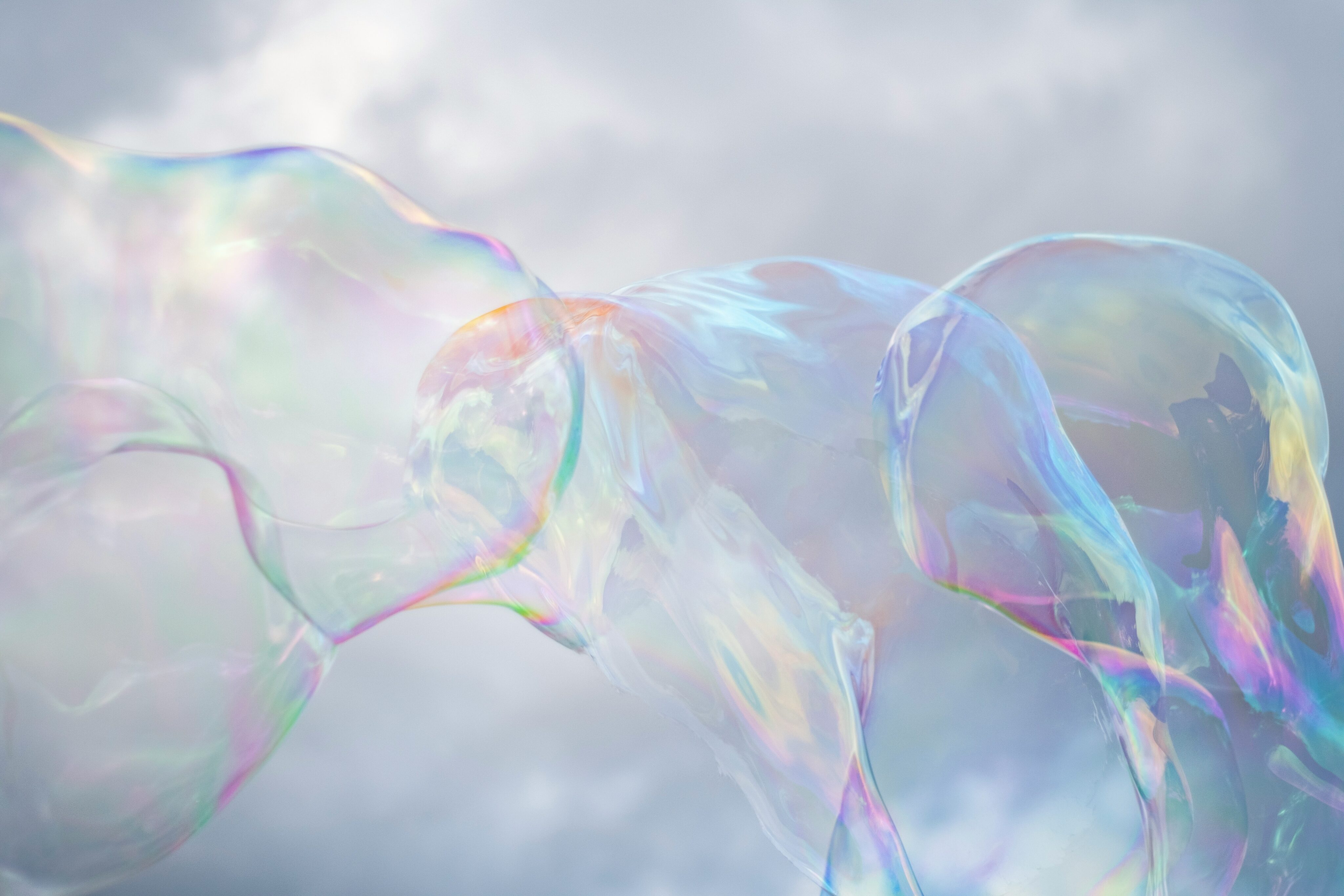 Aphtes dans la bouche : de grosses bulles de savon scintillent de différentes couleurs sur fond de ciel nuageux.