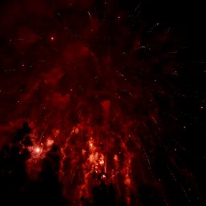 Sepsis Symptome:Feuerwerk leuchtet in intensiven Rottönen, Funken regnen vor einem nachtschwarzen Himmel herab.