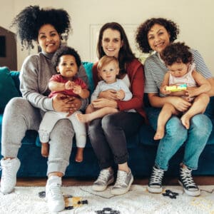 Semaglutid Schwangerschaft: Drei Frauen sitzen zusammen mit ihren Babys auf dem Sofa nebeneinander